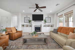 Living room featuring recessed lighting, visible vents, wood finished floors, and a stone fireplace