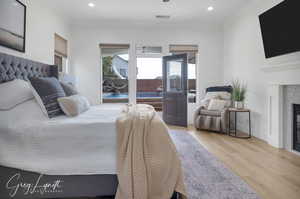 Bedroom with ornamental molding, a glass covered fireplace, visible vents, and wood finished floors