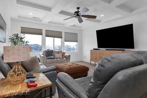 Living area featuring ceiling fan, coffered ceiling, visible vents, baseboards, and beamed ceiling