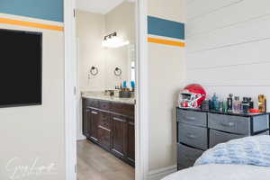 Bedroom featuring light wood-style flooring, a sink, and ensuite bathroom