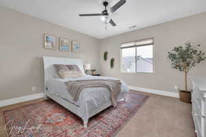 Bedroom featuring light carpet, baseboards, visible vents, and a ceiling fan