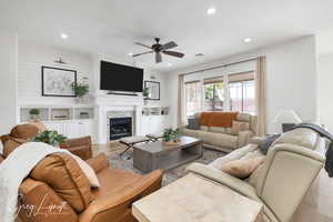 Living room with visible vents, a ceiling fan, wood finished floors, a stone fireplace, and recessed lighting