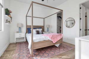 Bedroom featuring light wood-type flooring, baseboards, and a walk in closet