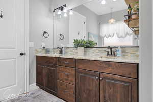 Full bathroom with double vanity, tasteful backsplash, and a sink