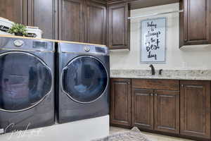 Clothes washing area featuring cabinet space, a sink, and independent washer and dryer