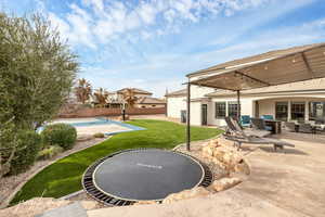 View of yard featuring a trampoline, fence, and a patio