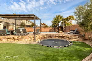 View of yard with a trampoline, a patio area, a fenced backyard, and a fenced in pool