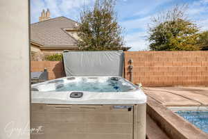 View of patio featuring fence and a hot tub