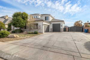 View of front of home featuring a garage, stone siding, driveway, a gate, and stucco siding