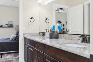 Ensuite bathroom featuring double vanity, a sink, and a ceiling fan