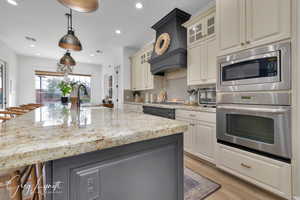 Kitchen with a sink, visible vents, appliances with stainless steel finishes, backsplash, and light stone countertops