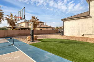 View of sport court with a lawn and fence