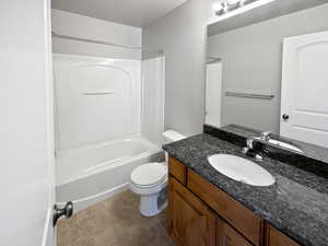 Bathroom with tile patterned flooring, tub / shower combination, vanity, and toilet