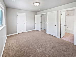 Unfurnished bedroom featuring connected bathroom, baseboards, and carpet flooring