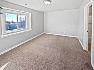 Carpeted empty room featuring visible vents and baseboards