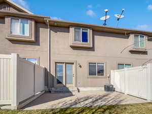 Back of property featuring entry steps, a patio area, fence, and stucco siding