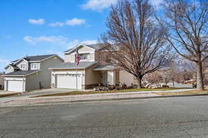 Traditional-style home with an attached garage, concrete driveway, and roof with shingles