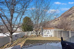 View of yard with an outdoor structure, a fenced backyard, and a gate