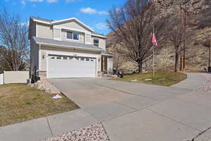 Traditional-style house featuring driveway, a garage, fence, a front lawn, and brick siding