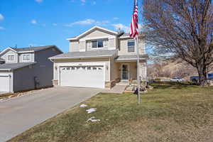 View of front facade featuring roof with shingles, brick siding, concrete driveway, a front yard, and a garage