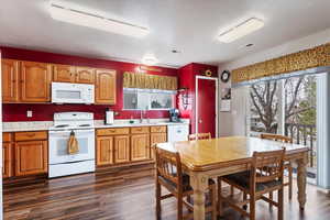 Kitchen with dark wood-style floors, white appliances, light countertops, and a sink