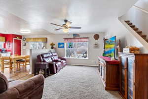 Living room featuring a textured ceiling, carpet floors, baseboards, and a healthy amount of sunlight