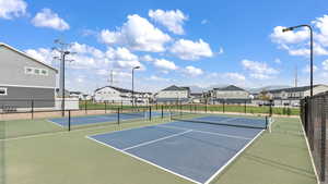 View of tennis court featuring a residential view and fence