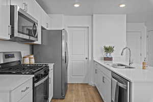 Kitchen with stainless steel appliances, a peninsula, a sink, and light countertops