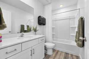 Full bath with vanity, wood finished floors, toilet, and shower / bathtub combination with curtain