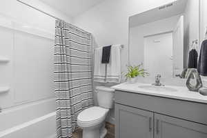 Bathroom with toilet, shower / tub combo, wood finished floors, vanity, and visible vents