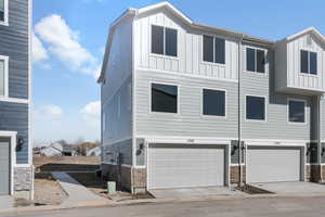 Multi unit property featuring a garage, stone siding, board and batten siding, and central AC