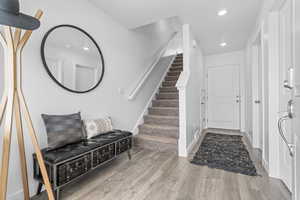 Entryway featuring stairs, baseboards, wood finished floors, and recessed lighting