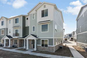 View of property featuring board and batten siding, a residential view, stone siding, and central AC unit