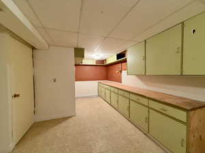 Green cabinets, a paneled ceiling and work area/extra storage