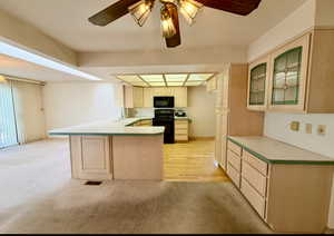 Kitchen featuring a skylight, kitchen cabinets, pantry, stove, a peninsula