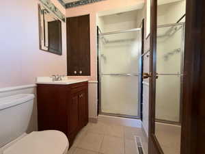 Master bathroom with toilet, a stall shower, tile patterned flooring, and vanity