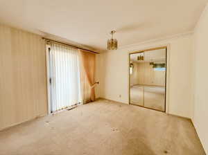 Bedroom featuring a chandelier, visible vents, ornamental molding, and light colored carpet