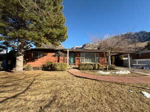 Ranch-style home with driveway, a front lawn, a carport, and brick siding