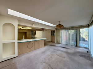 Interior space featuring a skylight, visible vents, a ceiling fan, light carpet