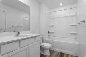 Full bathroom with vanity, shower / bath combination, wood finished floors, and toilet