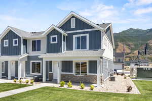 View of front of house featuring stone siding, a shingled roof, and board and batten siding