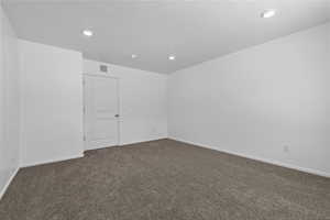 Spare room featuring dark colored carpet, visible vents, a textured ceiling, and recessed lighting