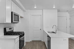 Kitchen with appliances with stainless steel finishes, a sink, a peninsula, and wood finished floors