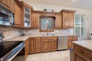 Kitchen with stainless steel appliances, brown cabinetry, and a sink