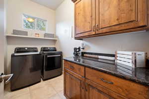 Washroom featuring separate washer and dryer, light tile patterned flooring, and cabinet space