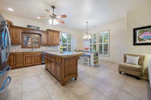 Kitchen with tasteful backsplash, a kitchen island, brown cabinets, stainless steel appliances, and a sink