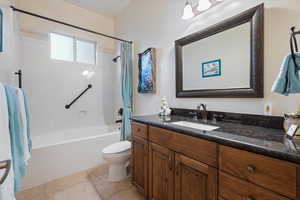 Full bathroom featuring toilet, shower / bathtub combination with curtain, vanity, and tile patterned floors