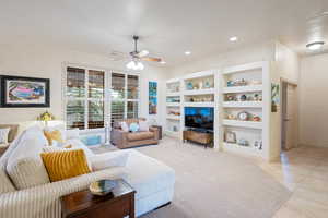 Living room with ceiling fan, built in shelves, recessed lighting, visible vents, and baseboards