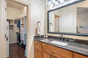 Bathroom featuring a spacious closet, vanity, and wood finished floors