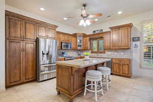 Kitchen with a kitchen breakfast bar, appliances with stainless steel finishes, visible vents, and brown cabinets